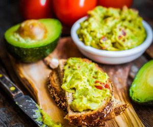 Guacamaole with bread and avocado on rustic wooden background